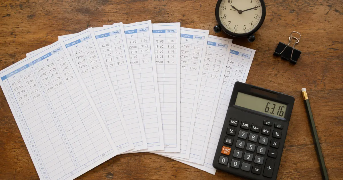Registros diários, calculadora e relógio usados para somar horas